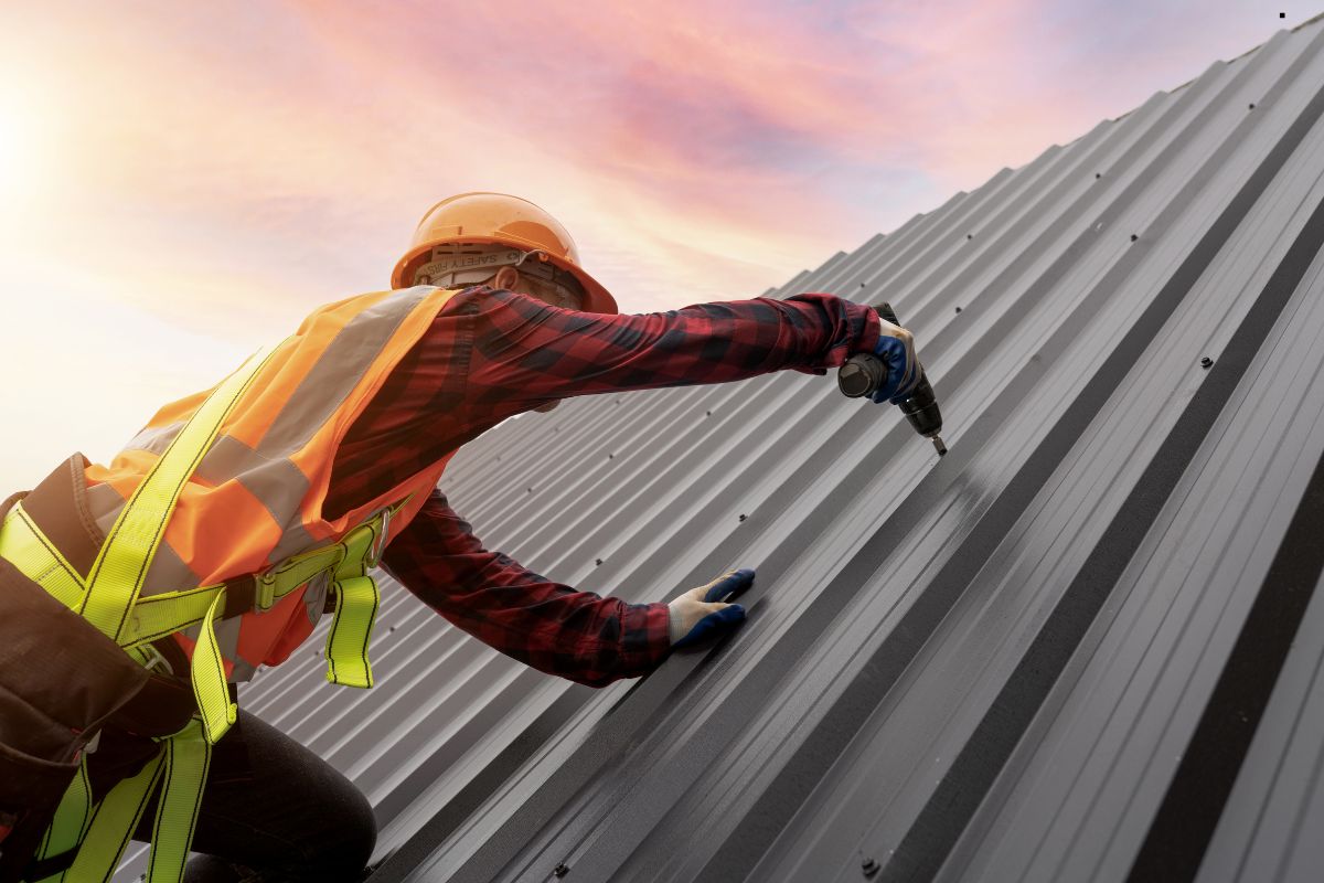 A man in safety gear diligently working on a metal roof, showcasing professional roofing services in action.